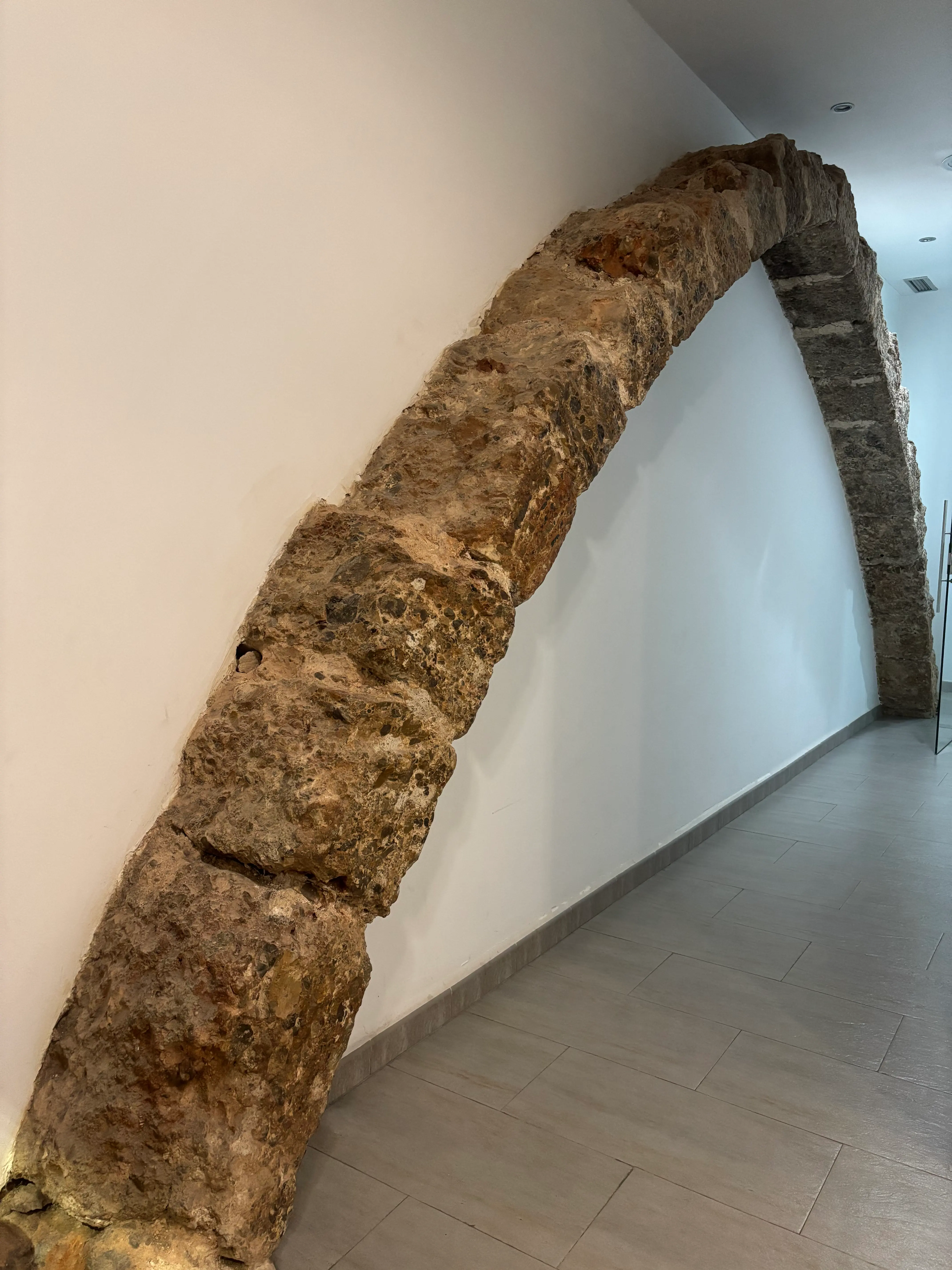 Arco de piedra sobresaliendo de la pared del pasillo de la planta baja de la clínica.