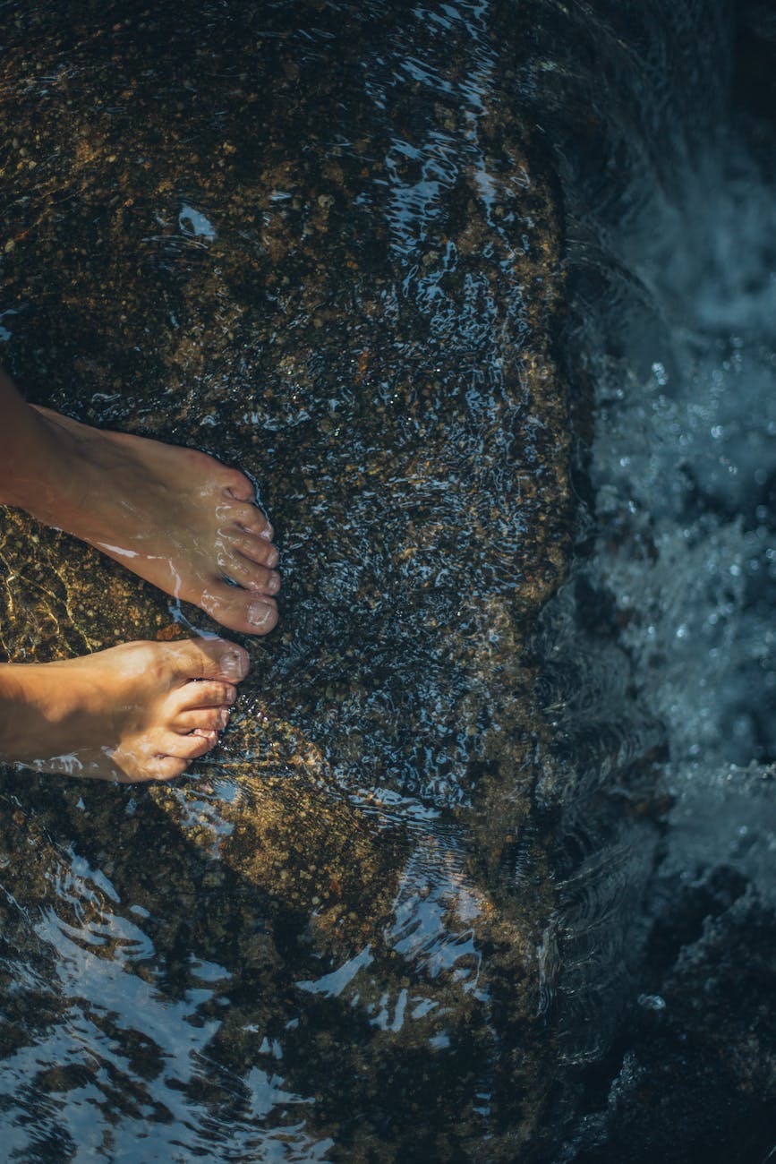 Pies de una persona mojados por el agua encima de una roca.